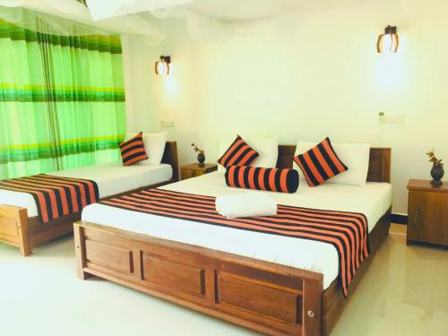 a bedroom with two beds with striped pillows at Sigiriya Ranasinghe Nature Villa in Sigiriya