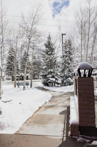a snow covered street with trees and a sidewalk at The Viking Lodge - Downtown Winter Park Colorado in Winter Park