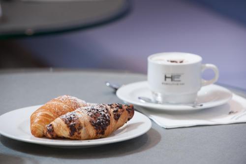 two croissants and a cup of coffee on a table at Executive Inn Boutique Hotel in Brindisi