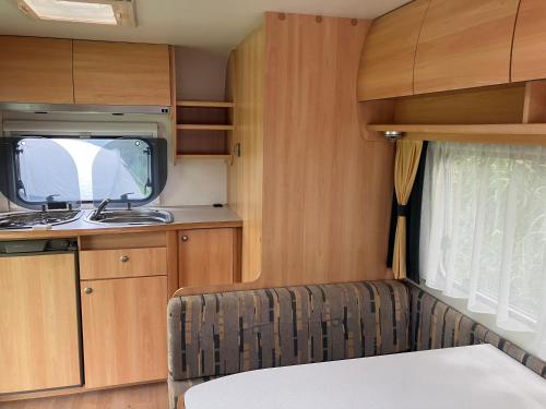 a small kitchen with a sink and a microwave in a caravan at Caravan met wijds uitzicht in Kuinre