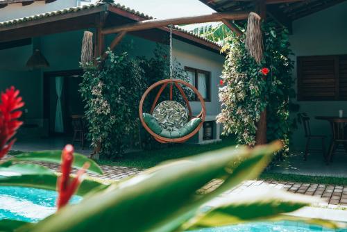 un jardin avec une balançoire à côté d'une piscine dans l'établissement Tropicália chalés boutique, à Pipa