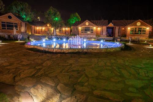 a fountain with lights in a yard at night at نزل المنتجع السياحية in Al Namas
