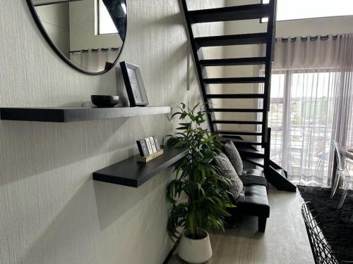 a staircase with a mirror and a plant in a room at Secure Executive Broadacres Apartment in Sandton
