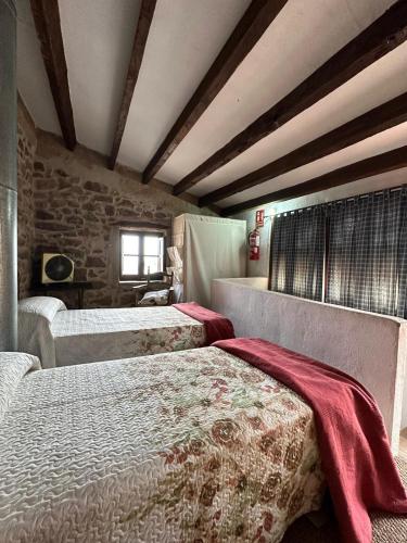 a bedroom with two beds and a stone wall at Casa Castillo in Vilafamés