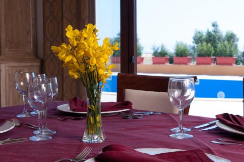 a vase of yellow flowers on a table with glasses at Hotel Donna Carmela Sede Unica a Sciacca in Sciacca