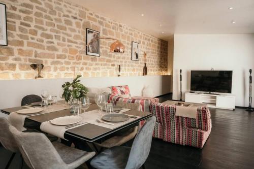 a dining room with a table and a brick wall at Le Grand Arches in Charleville-Mézières