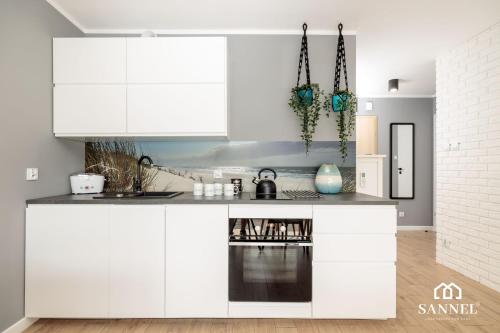 una cocina blanca con armarios y electrodomésticos blancos en Apartament West Sea-Słoneczne Tarasy Dziwnówek en Dziwnówek