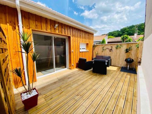 une terrasse en bois avec mobilier sur une maison dans l'établissement Chalet cosy secteur calme TRAM A 120 m gare aéroport, à Cenon
