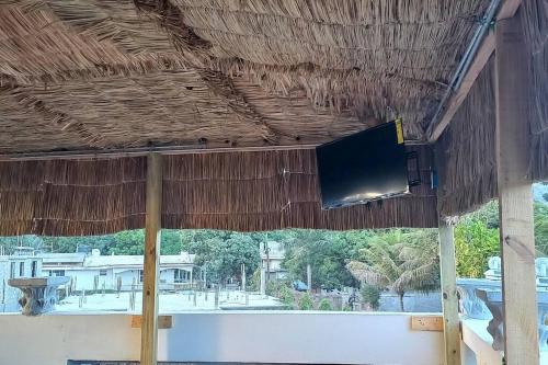 TV de pantalla plana colgada de un techo de paja en KING vacation Home en Cabo Haitiano