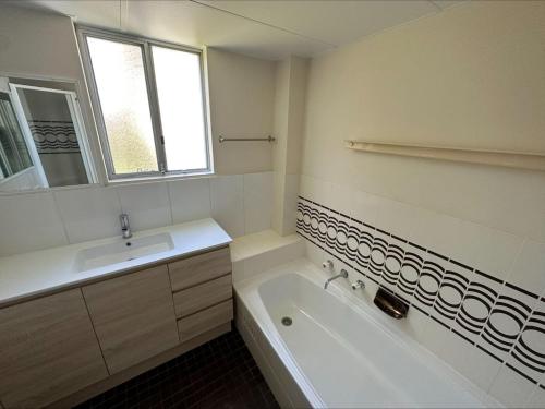a bathroom with a sink and a tub and a sink and a mirror at Beachpoint, Unit 101, 28 North Street in Forster