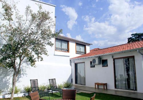 uma casa branca com cadeiras e uma árvore em Pousada Villa Tiradentes em Tiradentes