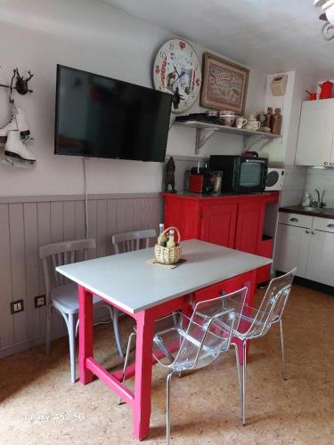 - une table et des chaises roses dans une cuisine avec une télévision dans l'établissement Appartement Cosy au cœur de Saint Lary, à Saint-Lary-Soulan