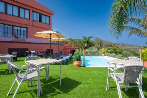 patio ze stołami i krzesłami oraz basenem w obiekcie Finca El Pastel w mieście Tacoronte