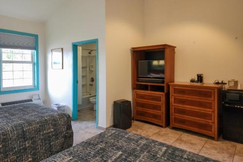 a bedroom with a bed and a dresser with a television at Ivey House Everglades Adventures Hotel in Everglades City
