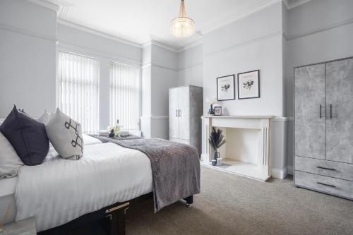 een witte slaapkamer met een bed en een open haard bij The Yorkshire Hosts - Central Castleford 4 Bed House - Free Parking in Castleford