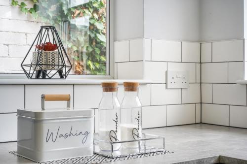 a bathroom with white tiled walls and two glass bottles at The Yorkshire Hosts - Central Castleford 4 Bed House - Free Parking in Castleford