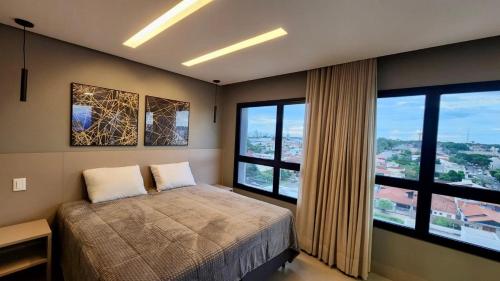 a bedroom with a bed and two large windows at Luxo e Exclusividade ao lado Shopping Campo Grande in Campo Grande