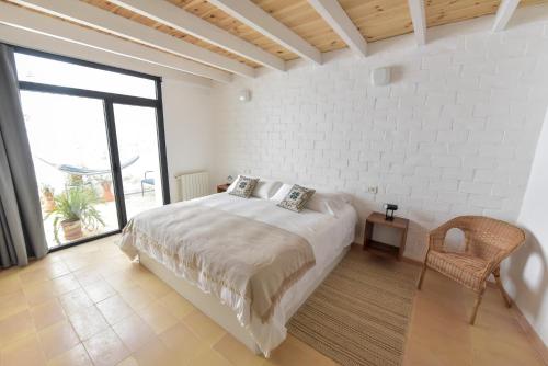 a white bedroom with a bed and a chair at Casa Botijo - Natural Design in Linares de la Sierra