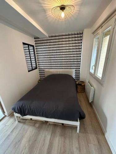 ein Schlafzimmer mit einem schwarzen Bett in einem Zimmer in der Unterkunft Victor Hugo 1 in Caudebec-lès-Elbeuf