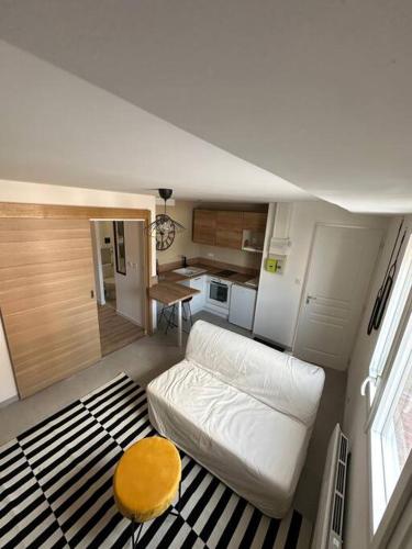 ein kleines Wohnzimmer mit einem weißen Sofa und einem Tisch in der Unterkunft Victor Hugo 1 in Caudebec-lès-Elbeuf
