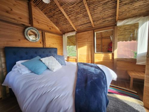 a bedroom with a large bed in a wooden room at Glamping El Muelle in Villa de Leyva