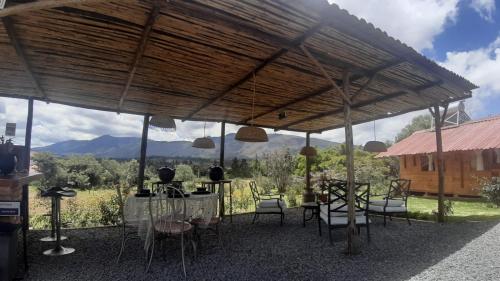 a patio with a table and chairs under a roof at Glamping El Muelle in Villa de Leyva