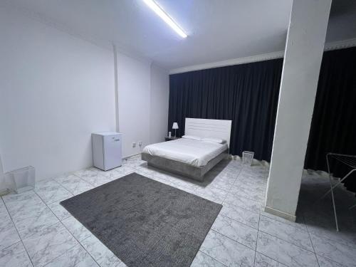 Habitación blanca con cama y alfombra en Dinar apartments, en Abu Dabi