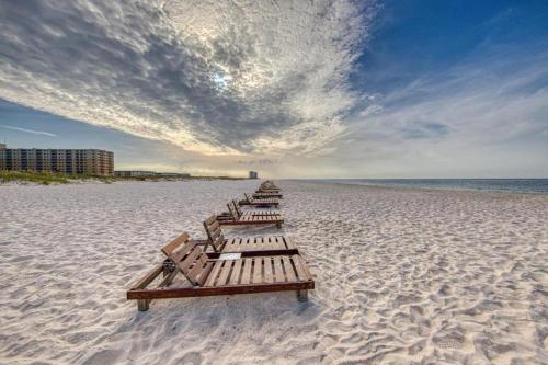 uma fila de bancos de madeira numa praia em Sugar Sands-Luxury 1st Floor 2BR 2BA Private Beach em Gulf Shores