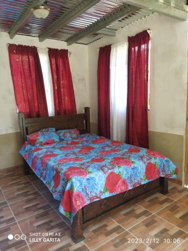 Bett in einem Zimmer mit roten Vorhängen in der Unterkunft Hospedaje Sauces - Cerro Chirripó in Herradura