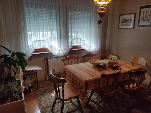 a dining room with a table and chairs and windows at Apartma Čampa in Kočevje