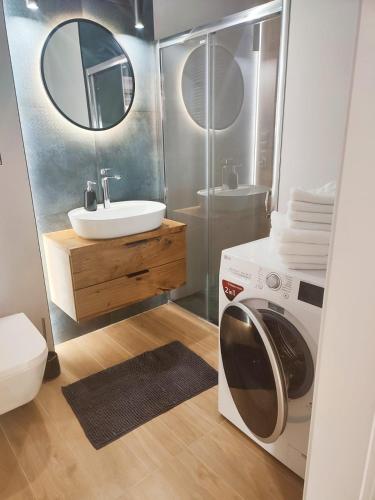 a bathroom with a washing machine and a sink at Miodowy Apartament in Złotów