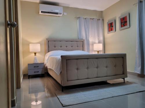 a bedroom with a bed and two lamps and a window at Apto Entero familiar espacioso con piscina confortable in Licey