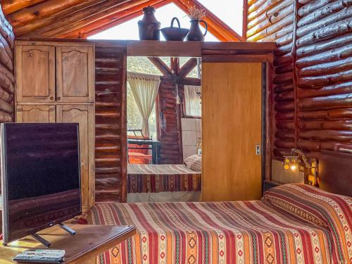a bedroom with two beds and a flat screen tv at Cabañas Aventurados in Potrerillos