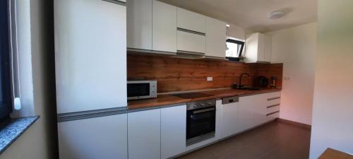 a kitchen with white cabinets and a microwave at Apartman Nina in Tuzla