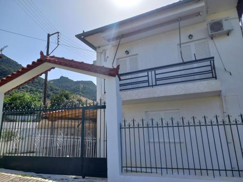 a white house with a gate and a balcony at TriΖin in Galatas