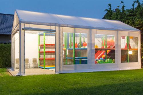 a white greenhouse with a playground in the grass at Willa Rodos II in Władysławowo