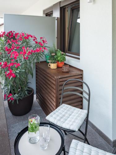a patio with a table and a chair and flowers at Dianthus Apartment in Lana
