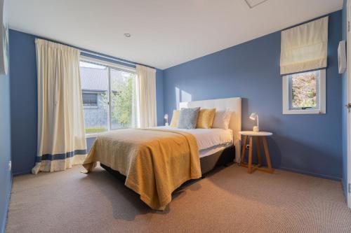 a blue bedroom with a bed and a window at Southland Sounds - Te Anau Holiday Home in Te Anau
