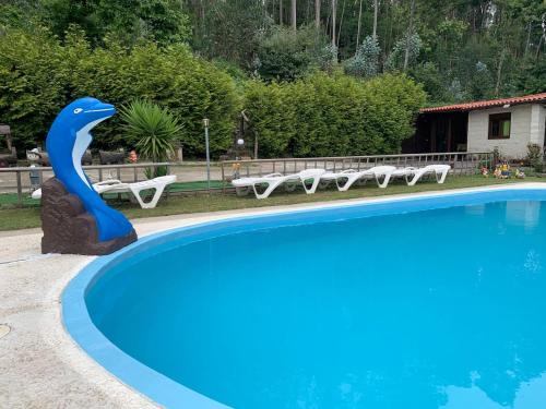 una piscina con una estatua de delfín junto a un grupo de sillas en Finca con dos casas rurales, en Randufe