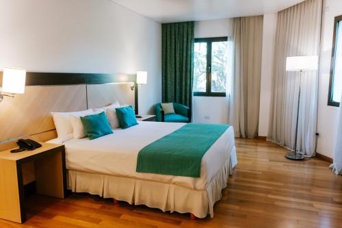 a hotel room with a large bed with blue pillows at Hotel Plaza Central Canning in Ezeiza