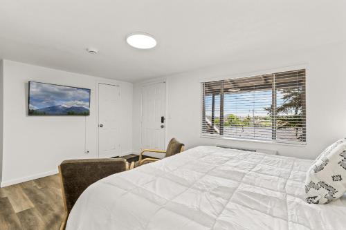 a white bedroom with a bed and a window at Venture at Route 66 in Flagstaff