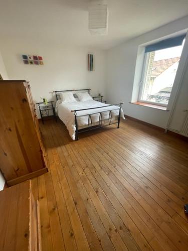een slaapkamer met een bed en een houten vloer bij Chez Mary et Stef in Verdun-sur-Meuse