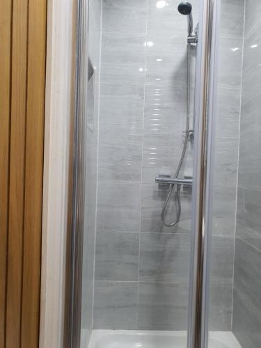 a shower with a glass door in a bathroom at Min Su Rooms in Stanwell