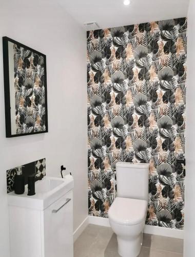 La salle de bains est pourvue de toilettes et d'un rideau de douche noir et blanc. dans l'établissement Le Repère de B&C, à Cenon