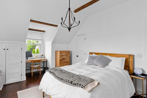 Habitación blanca con cama y escritorio en Cozy Greenport Cottage, en Greenport