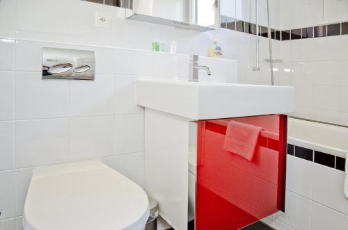 Chalet Adele في جريندلفالد: حمام مع حوض أبيض وخزانة حمراء