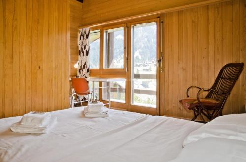 a bedroom with a bed and a chair and a window at Chalet Adele in Grindelwald