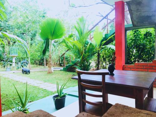 a wooden table and chair in a yard with plants at Sigiriya Ranasinghe Nature Villa & Cabana in Sigiriya