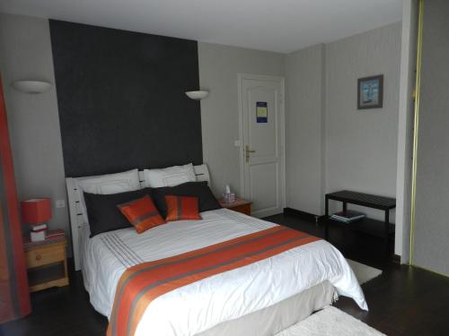 - une chambre avec un grand lit blanc et des oreillers orange dans l'établissement Aux Portes de Rennes Ch. d'hôtes, à Chartres-de-Bretagne