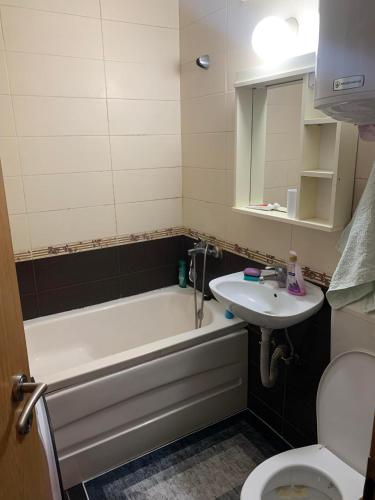 a bathroom with a tub and a sink and a toilet at Comfortable apartment close to the city center in Prishtinë